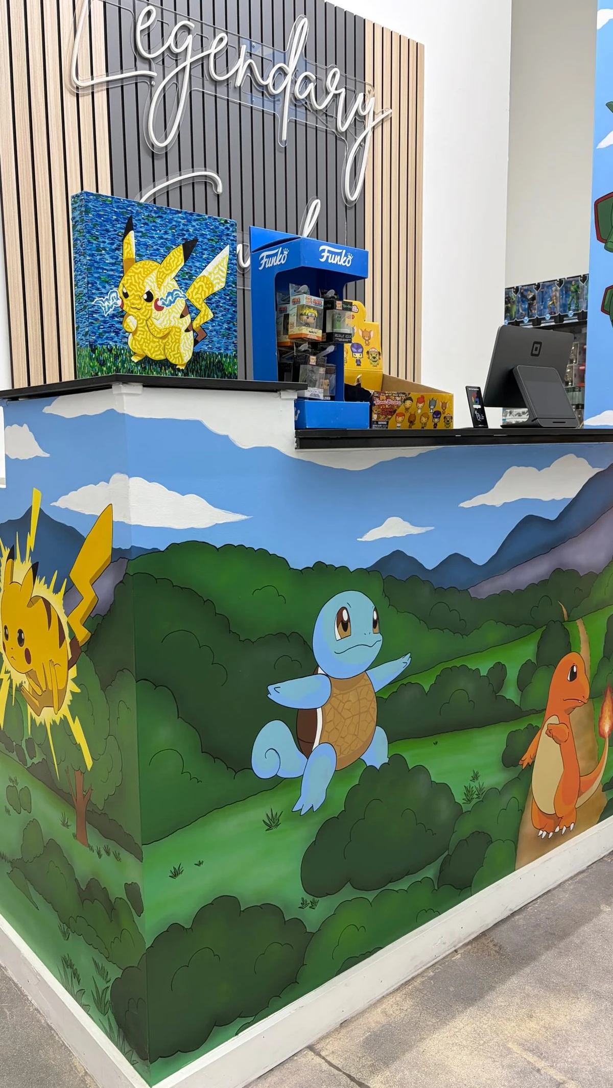 The Legendary Vault front counter with its hand-painted Pikachu, Squirtle and Charmander mural